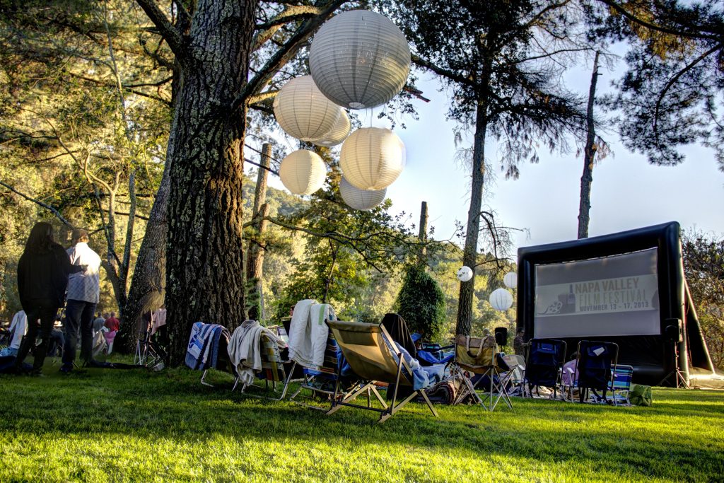 A film festival taking place with a FunFlicks inflatable screen at a local parks and recreation event.