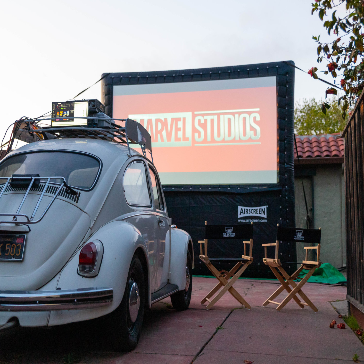 A private drive-in movie with a small movie theater screen in a backyard.