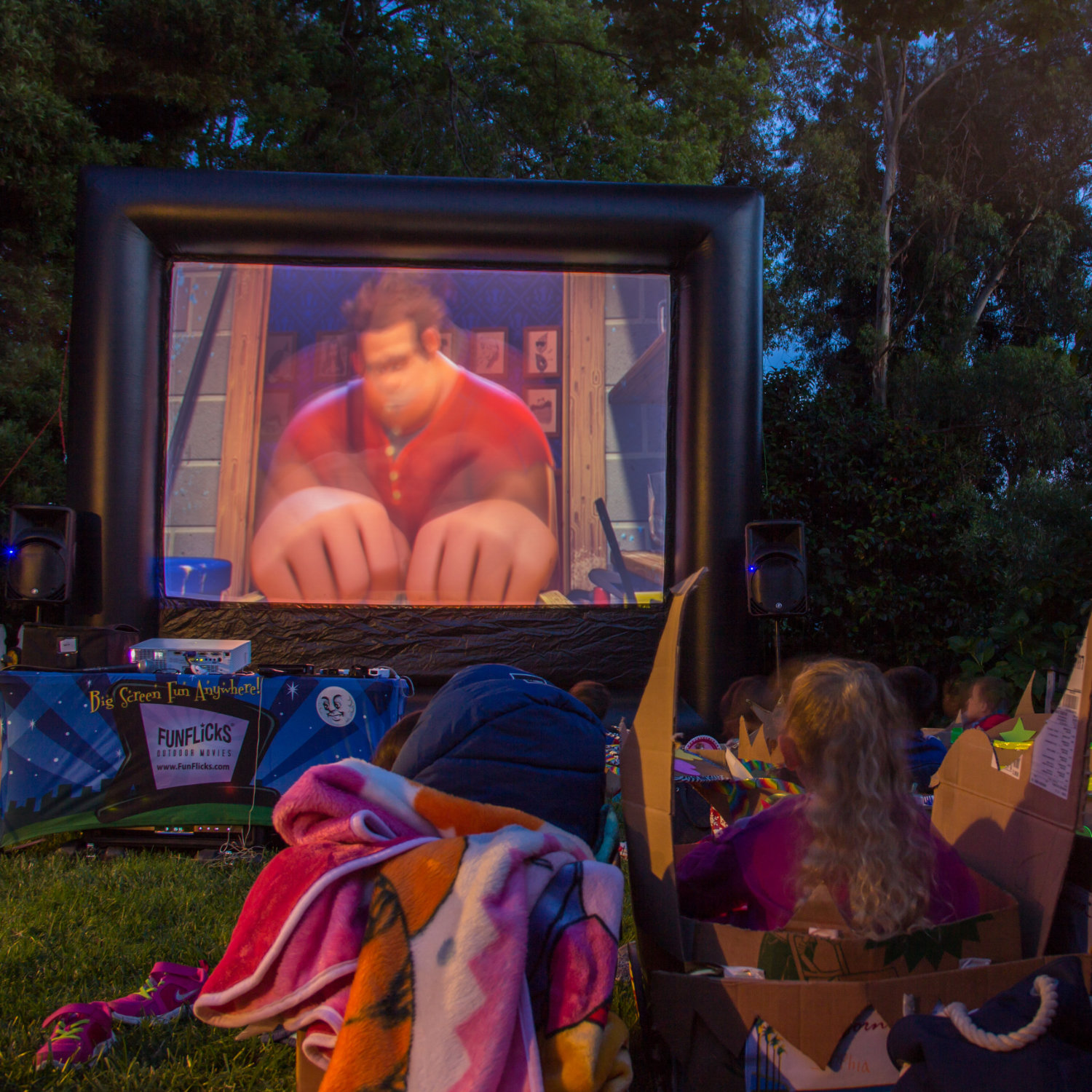 Kids having a mini drive-in movie with a FunFlicks inflatable screen in their crafted, cardboard cars