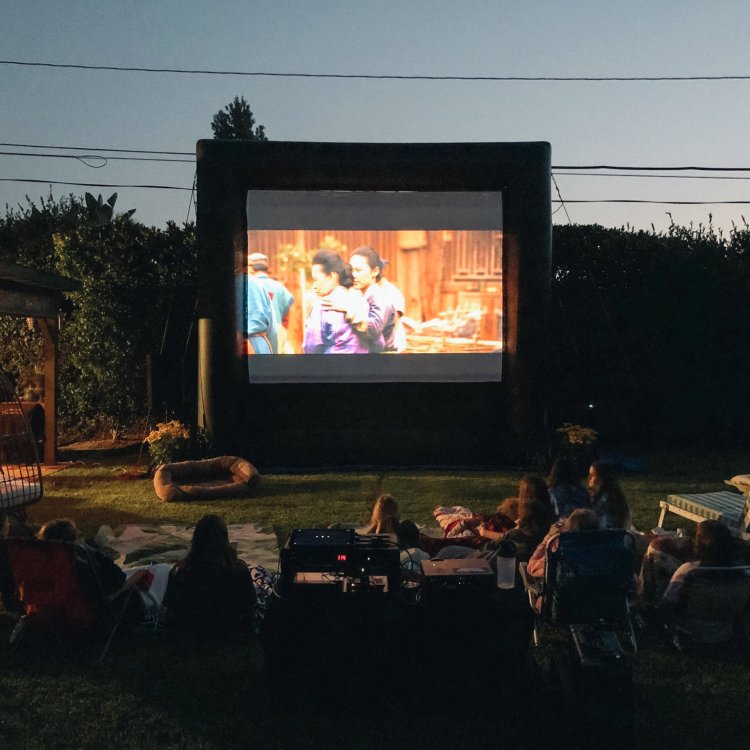 Family watching a movie on a FunFlicks inflatable screen in the privacy of their backyard.