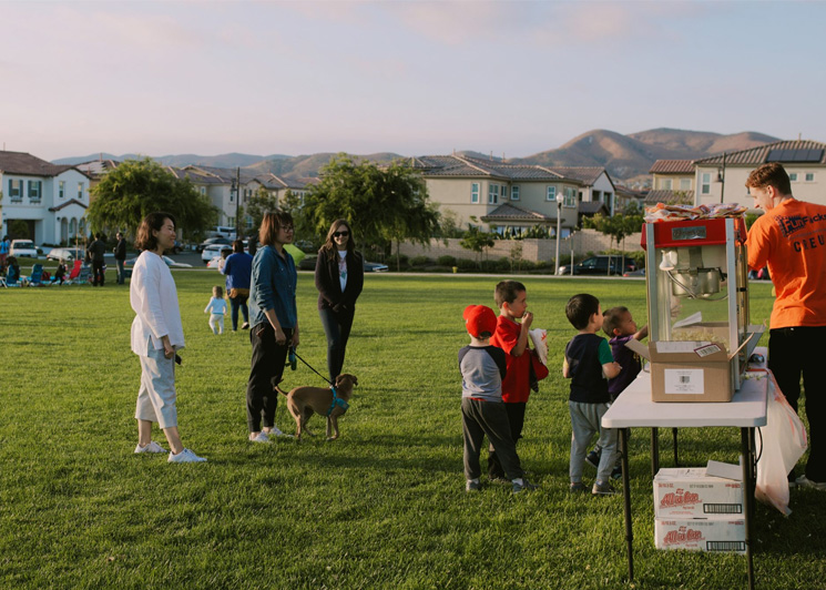 A FunFlicks event host serving guests popcorn at an outdoor movie party