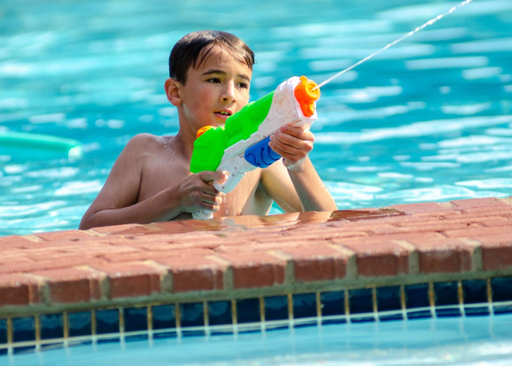 Boy shooting a water gun in the pool