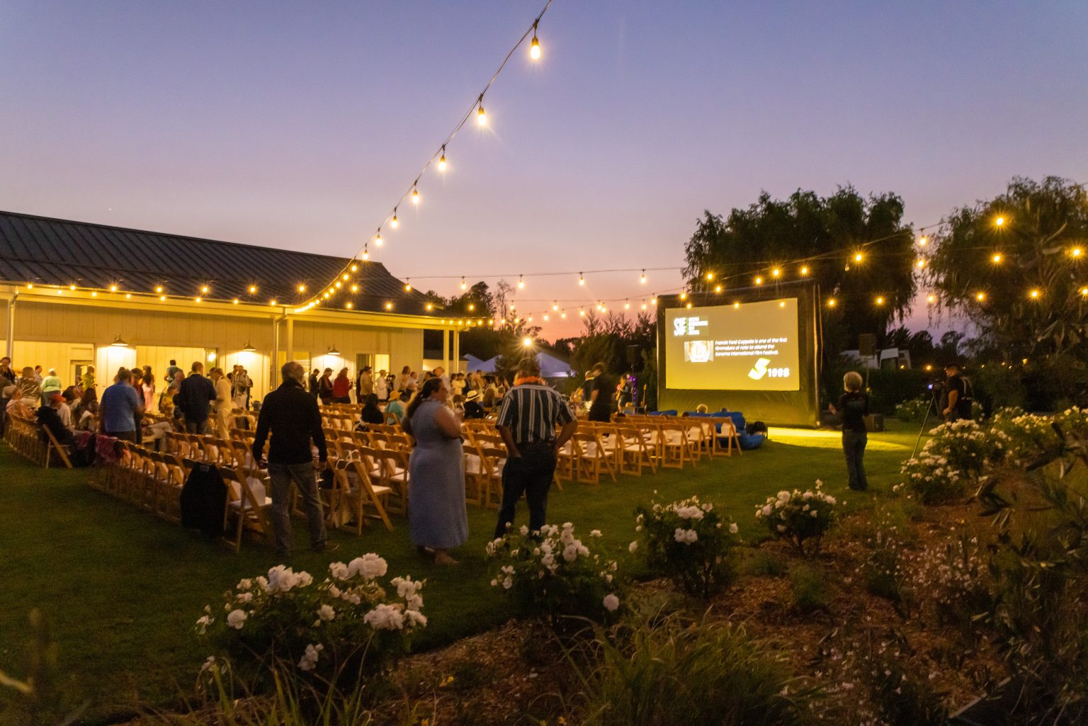 Family and friends watching a movie on a FunFlicks inflatable screen at their community country club.
