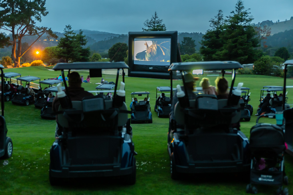 Family and friends watching a movie on a FunFlicks inflatable screen at their community country club.