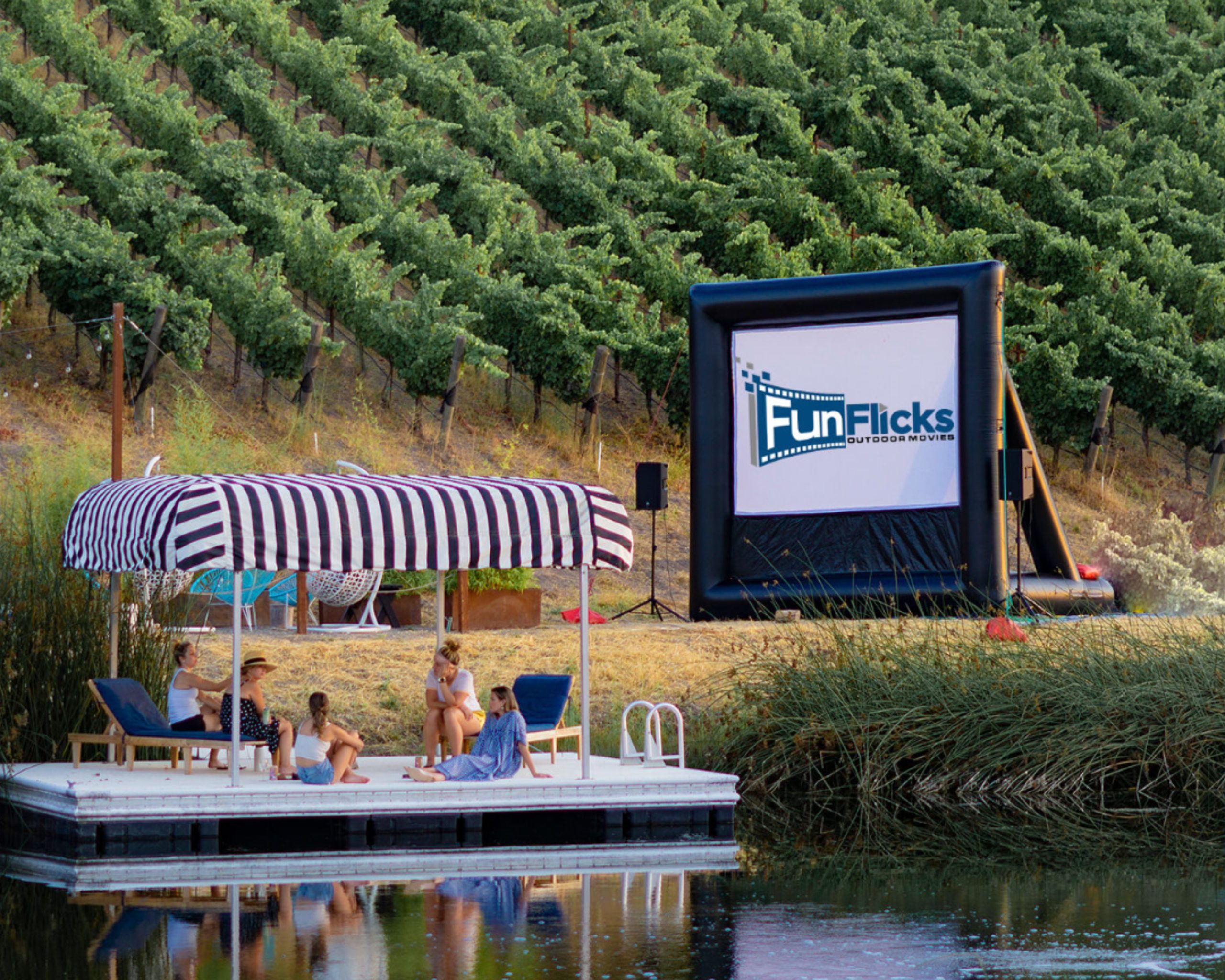 Family and friends watching a movie on a FunFlicks inflatable screen at their community winery.