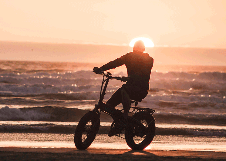 Biker riding on the beach at sunset